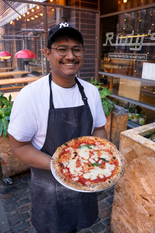 staff holding neapolitan pizza