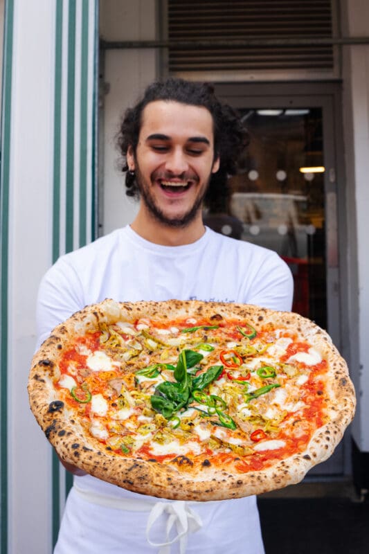 staff holding true neapolitan pizza
