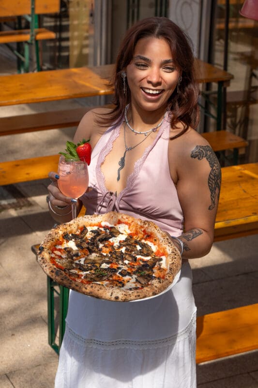 woman holding drink and neapolitan style pizza
