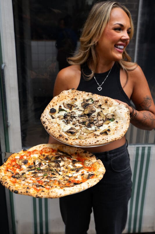 person holding two neapolitan style pizzas