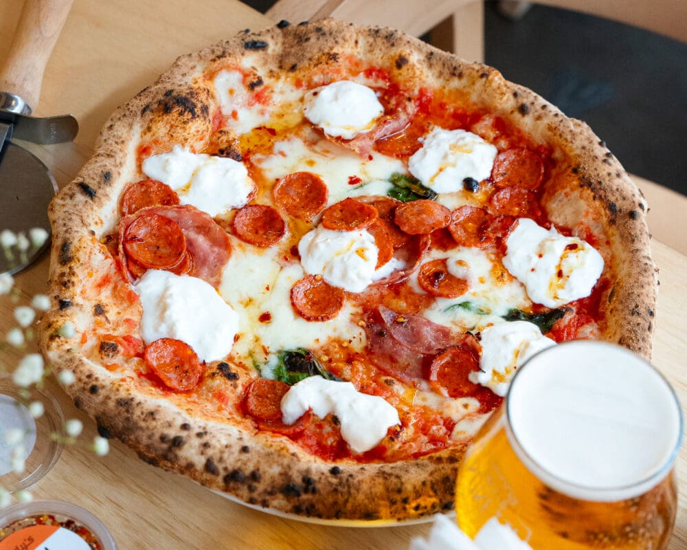 tomato based pepperoni pizza with beer on the side