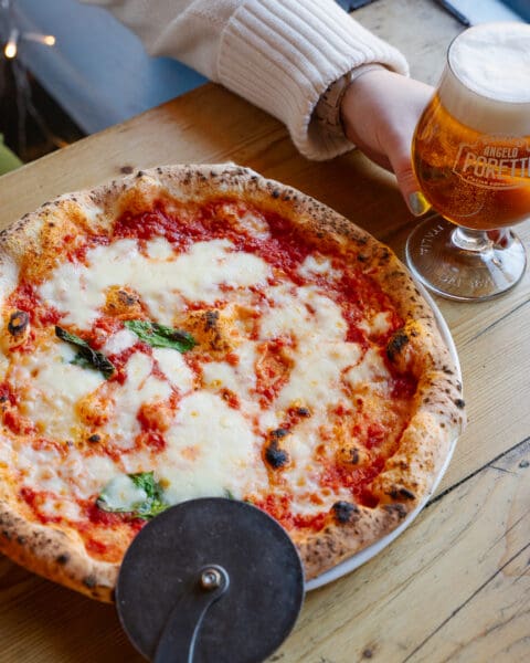 authentic neapolitan pizza with cheese and pizza cutter wheel on the side