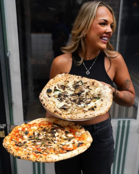 woman holding two pizzas